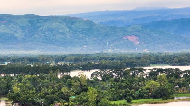 Aerial view of Tanguar Haor wetlands with lush green trees and rolling hills under an overcast sky in Sunamganj District, Sylhet Division, Bangladesh.