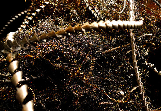 Steel scrap background. Metal chip waste after machining metal parts on cnc lathe. Metal twisted spiral steel shavings. Shiny silver confetti, fine glitter on dark background. 