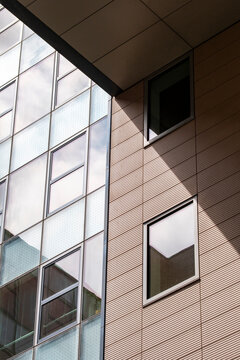 A shaded corner of modern building facade turns architecture, window placement, balcony edge, urban shadow, and cladding into abstract geometry