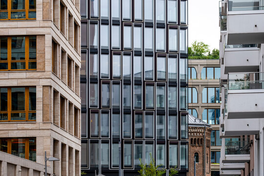 Glass and brick layers compress around a modern building facade where architecture, window rhythm, balcony edges, and urban depth share the frame