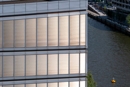 Water runs beside a Berlin, Germany facade where a modern building, window grid, architecture, river edge, and reflection form a quiet urban view