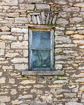 Background of a dilapidated stone block building wall with an old window