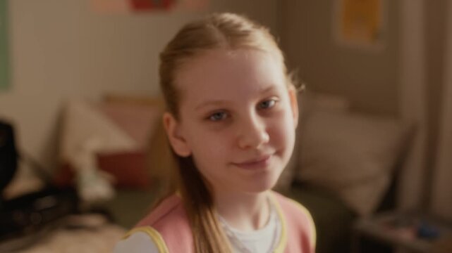 Portrait of Caucasian girl playing silver flute during music lesson at home, lowering instrument and smiling at camera. Video is ideal for promoting music education and children tutoring services