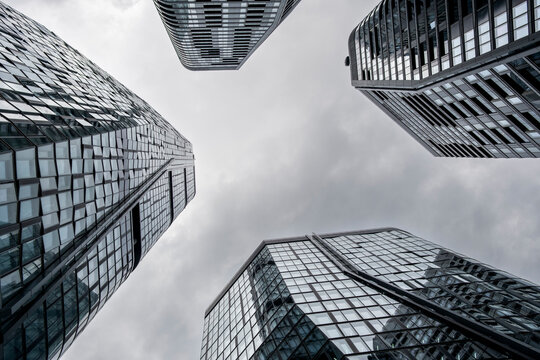 Looking up between Frankfurt, Germany glass towers, modern financial architecture forms an urban canyon of reflective facades under gray sky