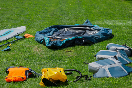 inflatable boat layout background green grass surface deflated kayak parts pump life jacket seats unboxing equipment active summer lifestyle concept of tourism, water sports, outdoor recreation