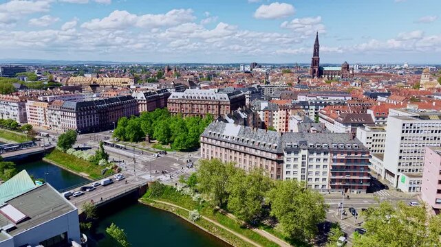 Salle des fetes de la bourse building near river with Notre Dame cathedral in background in Strasbourg, France. Aerial forward, cityscape