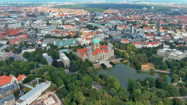 4K aerial drone view of Hannover, Germany. Panoramic cityscape featuring the magnificent New Town Hall (Neues Rathaus), Maschpark, and city skyline.