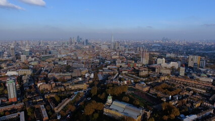 Obraz premium 4K aerial drone view of the London skyline featuring the Imperial War Museum, The Shard, and the City financial district under a clear blue sky.