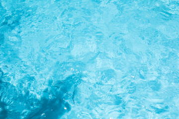 Obraz na płótnie Canvas Top view of crystal clear blue swimming pool water texture with gentle ripples and sunlight reflections for summer background.