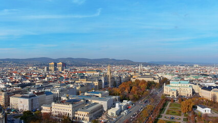 Fototapeta premium 4K aerial drone image of Vienna, Austria. Beautiful autumn cityscape panorama featuring the Burgtheater, Rathaus, and Ringstrasse boulevard.