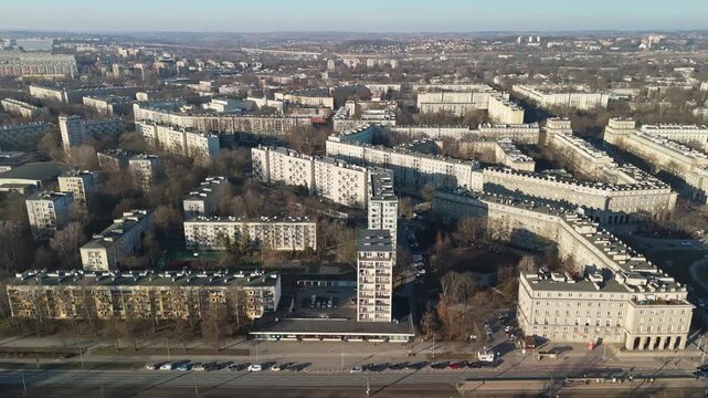 In Nowa Huta, Krak&oacute;w, residential apartment blocks and green spaces form a mid‑century urban grid centered on a main avenue and roundabouts, viewed in a drone cityscape.