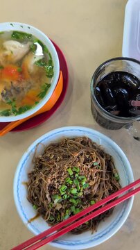 High angle view of Malaysian Kon lo mee dry-tossed noodles and a bowl of fish soup