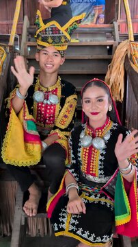Young man and girl waving and smiling with complete set of Dusun Tindal Clothes Sinipak during Harvest Festival in Sabah