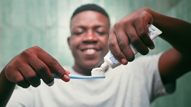 Young Black Man Squeezing Toothpaste Onto a Toothbrush for Daily Dental Hygiene and Oral Care