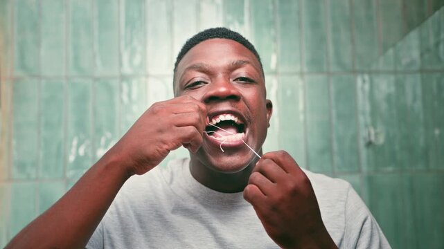 Young Black Man Diligently Flossing Teeth for Excellent Oral Hygiene and a Healthy Smile