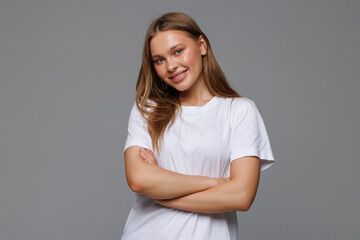 Fototapeta premium Young woman smiling and crossing her arms looking like a boss on white background