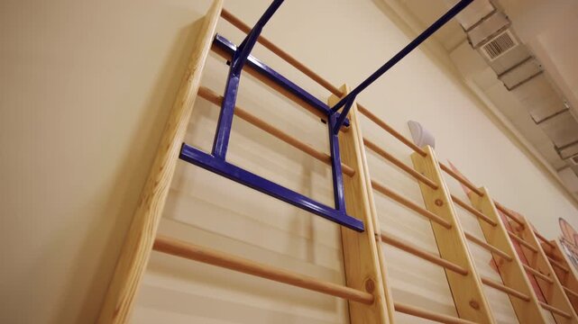 Pull up bars hang on ladder in modern school gym low angle shot. Sports equipment to train arm muscles at athletic club. Fitness inventory