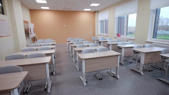 Empty elementary school classroom with desks arranged in rows. Contemporary interior design of room at education facility. Kids learning