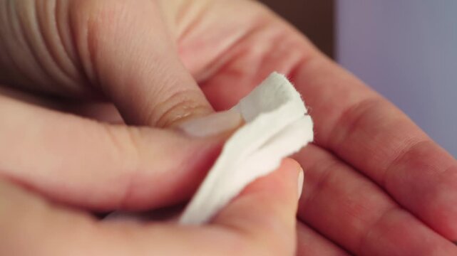 Close-up of hands removing nail polish with a cotton pad and nail polish remover. Beauty routine, manicure care, personal grooming, and self-care concept at home. High quality 4k footage