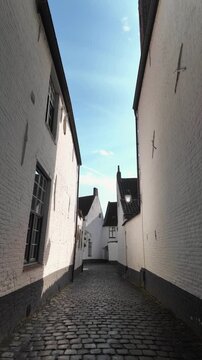 Historic UNESCO Courtrai beguinage alley walkthrough as the camera advances through the narrow cobbled passage of the heritage site.