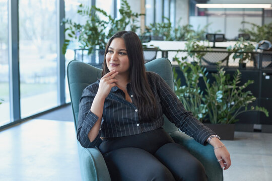 A woman is sitting in a chair with her hands on her chin