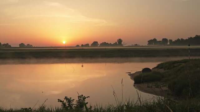 Fishing rods positioned along the misty banks of Elbe River at dawn. Peaceful outdoor scene, angling hobby and natural beauty of Germany.