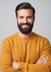 Fototapeta premium Confident Smiling Man with Beard Wearing Yellow Sweater Standing with Arms Crossed on Gray Background
