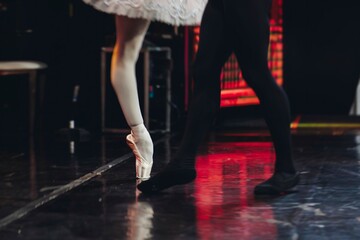 Ballet dancers couple during performance repetition, classic ballet rehearsal practicing in ballroom, view of legs in pointe shoes, ballerina and ballet dancer on a concert hall theatre stage floor © tsuguliev