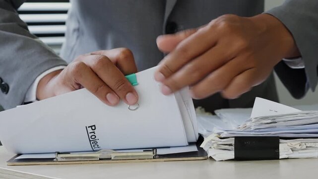 Busy business professional handling a large pile of administrative documents at desk, representing office workload, paperwork overload, records management, compliance review, and corporate tasks.