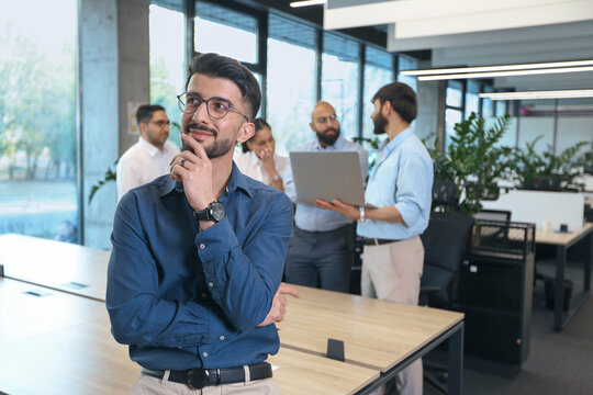 A man in a blue shirt is thinking while standing in front of a group of people