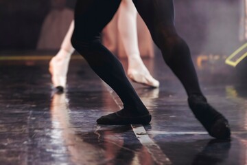 Ballet dancers couple during performance repetition, classic ballet rehearsal practicing in ballroom, view of legs in pointe shoes, ballerina and ballet dancer on a concert hall theatre stage floor © tsuguliev