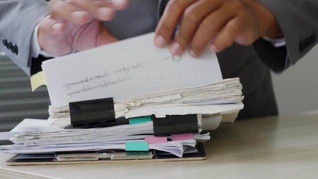 Adult accountant handling financial documents and reports at office desk, representing bookkeeping, tax preparation, audit review, invoice checking, budget records, and business finance.