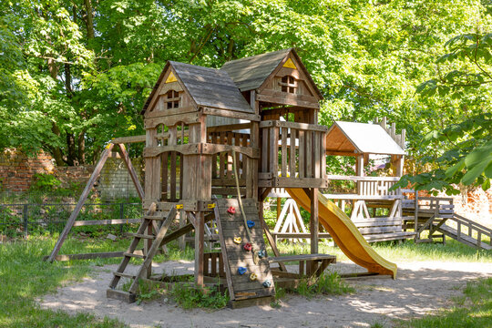 Wooden playhouse with slide and climbing wall in park on sunny day