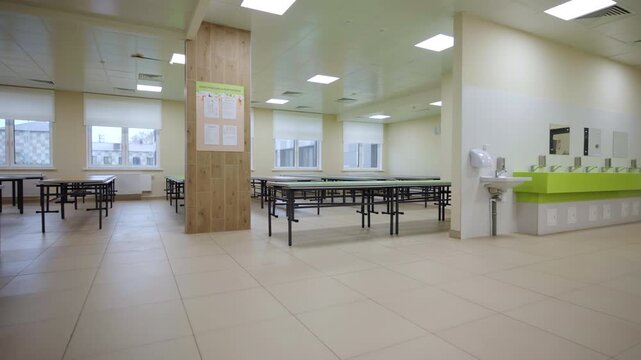 Stylish interior of school canteen with long tables and decorative columns. Children dining place maintained at education facility