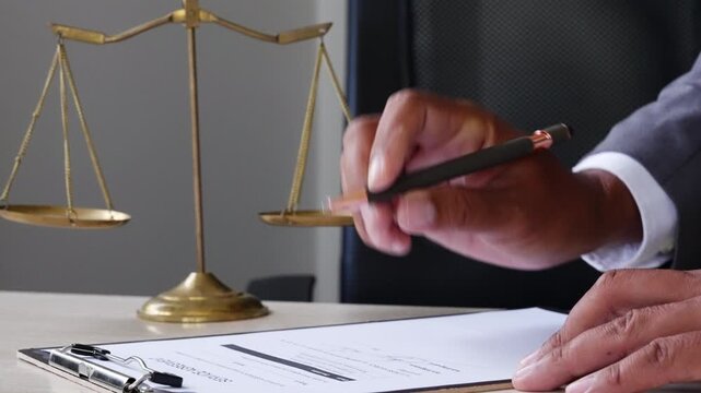 Attorney signing case documents near justice balance scale, representing litigation, lawsuit evidence, dispute settlement, court process, legal rights, and professional defense service.