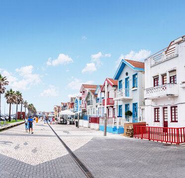 Iconic wooden houses with colorful vertical stripes under a clear blue sky in Costa Nova, Portugal.