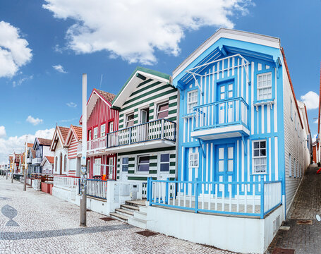 Iconic wooden houses with colorful vertical stripes under a clear blue sky in Costa Nova, Portugal.