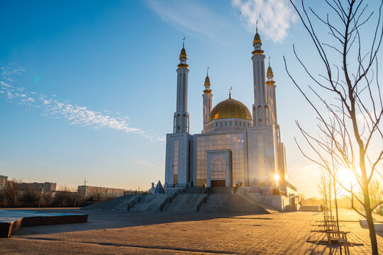 Nur Gasyr Mosque in Aktobe at sunset with a bright yellow sun, Kazakhstan