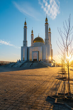 Nur Gasyr Mosque in Aktobe at sunset with a bright yellow sun, Kazakhstan