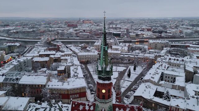 An aerial flyover of Krakow's Old Town in winter with a view of St. Joseph's Church in the evening.