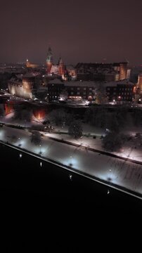 An aerial flyover of Wawel Castle in spring, covered in snow, on an evening in Poland.
