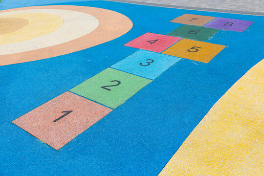 Colorful hopscotch game on modern playground with rubber safety surface