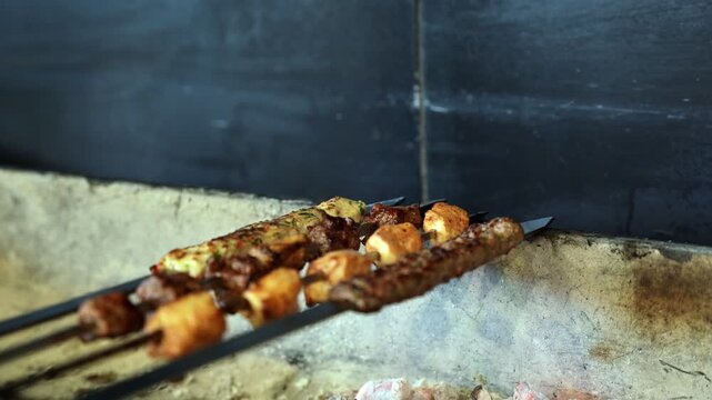 Close-up of traditional mixed grill kebabs and shish tawook being cooked on metal skewers in a professional restaurant kitchen. Cinematic shallow depth of field highlights the culinary texture.
