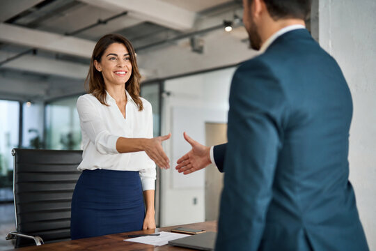 Confident and Smiling Businesswoman Reaching Out for a Handshake with Male Partner to conform a Deal in Modern Office