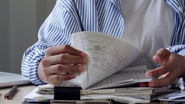 Female office worker reviewing a stack of paperwork on desk, showing document organization, file management, corporate administration, audit workflow, deadline pressure, and productivity.