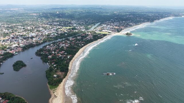 Aerial view of the Nilwala River meeting the Indian Ocean along a sandy beach and urban coastline in Matara, Southern Province, Sri Lanka.