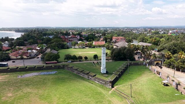 Aerial view of the historic Matara Fort and white Clock Tower surrounded by green lawns and the urban landscape of the city Matara, Southern Province, Sri Lanka.