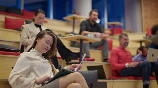 A group of diverse people engages in collaborative work and discussion within a contemporary office setting. Diverse colleagues are seen interacting and utilizing technology in an open workspace