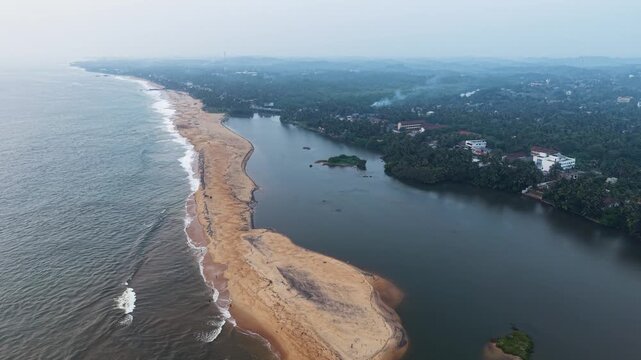 Aerial view of Mahamodara Lake separated from the ocean by a narrow sandy beach with lush tropical greenery and buildings in Galle, Southern Province, Sri Lanka.