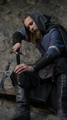 Fototapeta premium Weary warrior rests, hand on sword hilt amidst weathered stone.